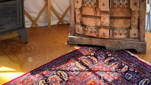 Ein Zimmer mit einem Holzkasten, einem gemusterten Teppich und einem Gitterfenster.