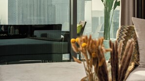 A modern living room with a large window, a sofa, a coffee table, and a plant. - Luxury 3.5BR Burj Khalifa LED View  (Dubai)
