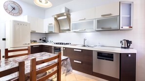 Une cuisine moderne avec une table à manger, des chaises, une horloge et un four encastré.
