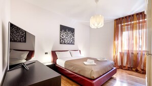 Une chambre d’hôtel moderne, équipée d’un lit, d’une table de chevet, d’œuvres d’art et offrant une vue sur l’extérieur.