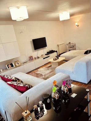 Un salon moderne comprenant deux canapés, un téléviseur à écran plat, une table basse et une petite table d’appoint.