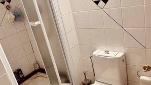 Une salle de bain avec des toilettes, une douche et une porte en verre.