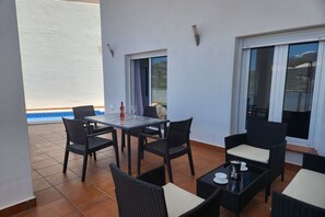 Eine Terrasse mit Tisch und Stühlen, einer Weinflasche und einem Glas.