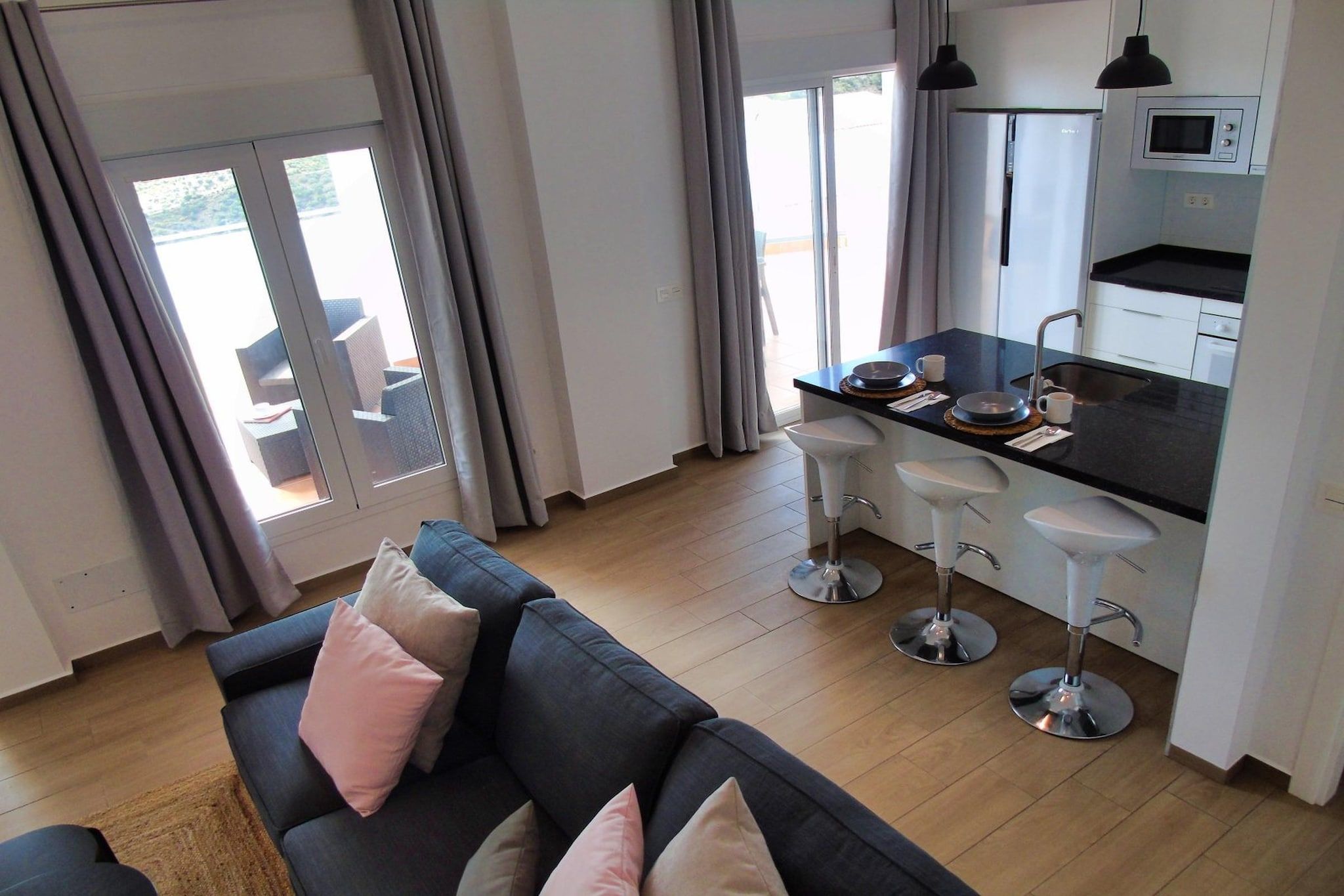 A modern living room with a sofa and a kitchen area with bar stools.