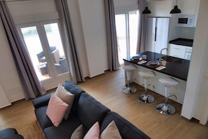 Ein modernes Wohnzimmer mit einer Couch und einer Küchenzeile mit Barhocker.
