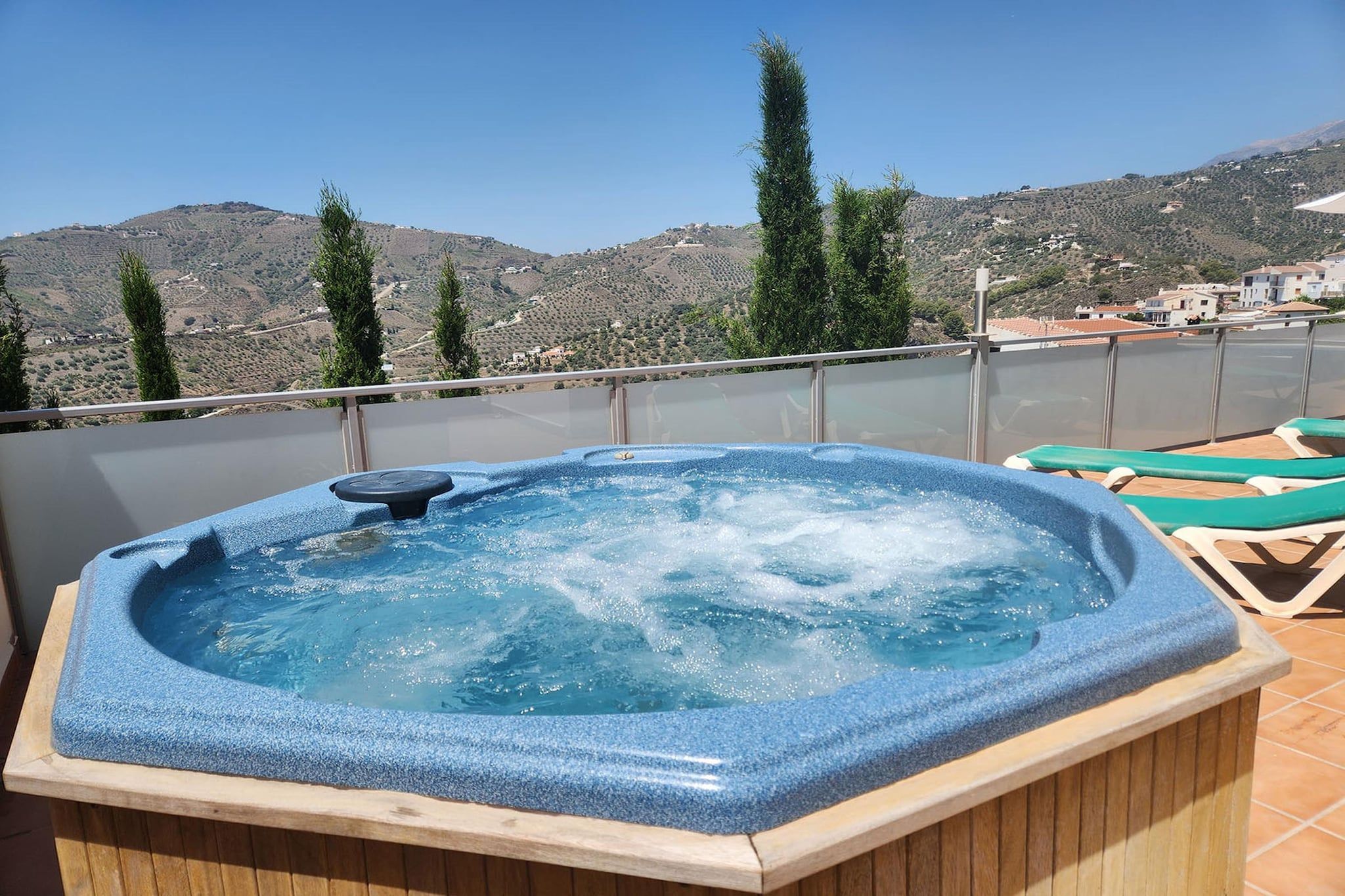 A hot tub on a balcony with a view of a hilly landscape.