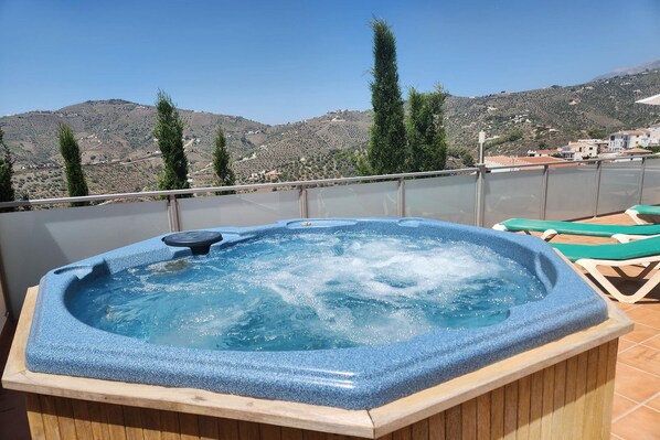 Ein Whirlpool auf einem Balkon mit Blick auf eine hügelige Landschaft.