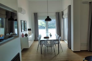 Ein moderner Essbereich mit Tisch, Stühlen, einer Pendelleuchte und Blick ins Freie.