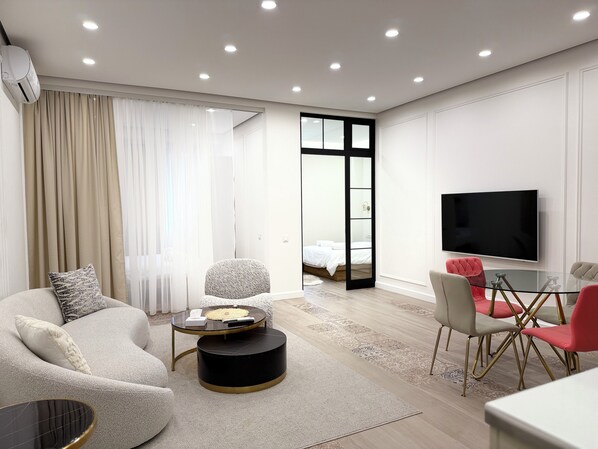 Een moderne woonkamer met een bank, een rond bijzettafeltje en een televisie.