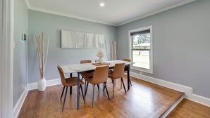 Een eethoek met een tafel, stoelen, een vaas en een raam.