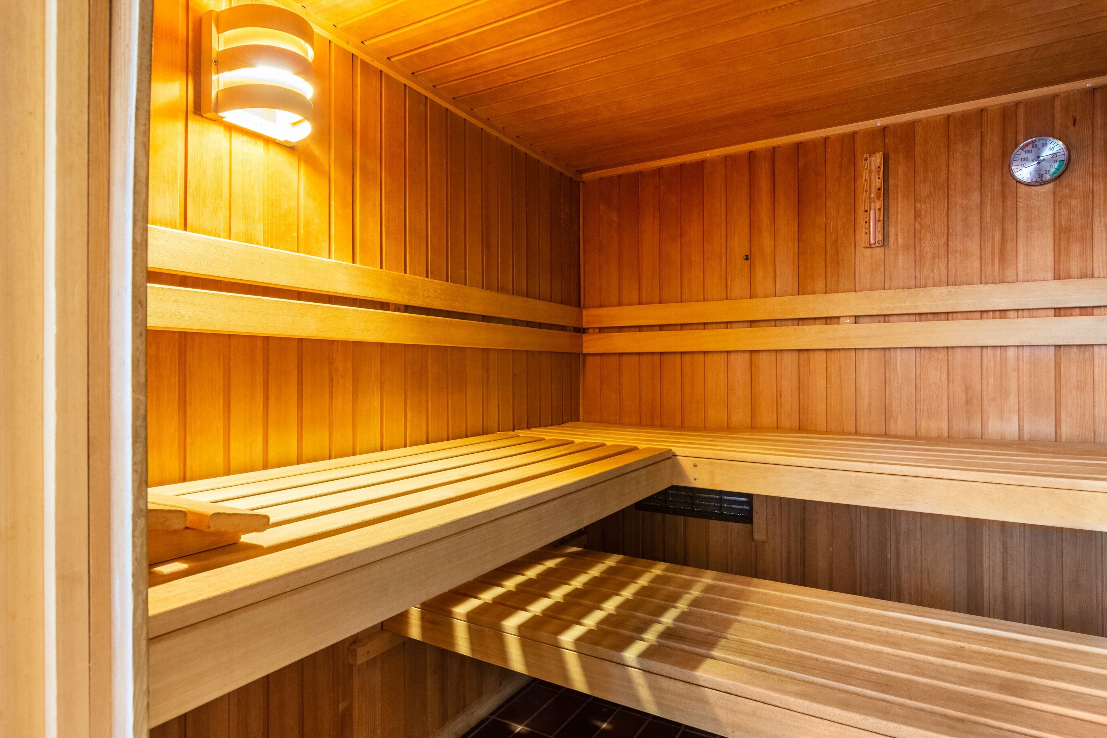 A sauna with wooden benches and a visible temperature gauge.
