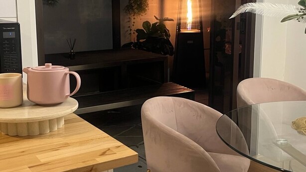 Eine moderne Küche mit einer Holzausziehtafel, einem rosafarbenen Teekessel und einem Glastisch mit einem Stuhl.