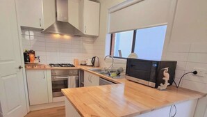 Eine moderne Küche mit weißen Schränken, einer Holz Arbeitsplatte, einem Gasherd und einem Einbauofen.