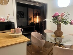 Una cocina moderna con microondas, cafetera y un florero con flores sobre una mesa de vidrio.