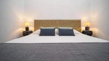 A bed with a woven headboard, two bedside lamps, and a grey throw blanket.