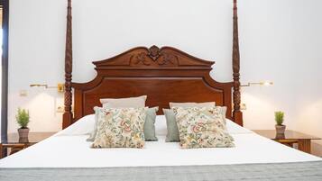Een bed met houten hoofdbord, twee nachtkastjes met lampen en kussens met bloemenprint.