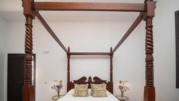 Ein Himmelbett mit Holzrahmen und einer grünen Bettdecke.