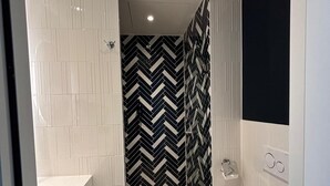 Un baño moderno con lavamanos, inodoro y zona de ducha blancos.