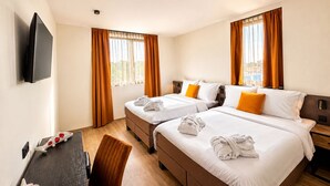 Habitación de hotel con dos camas, televisión, escritorio y silla.