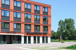 A hotel with a modern facade, large windows, and a clear view of the surrounding greenery. - Hotel het Dok (IJmuiden)