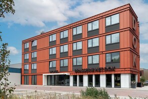 Un moderno edificio de hotel con fachada roja, múltiples ventanas y cielo despejado.