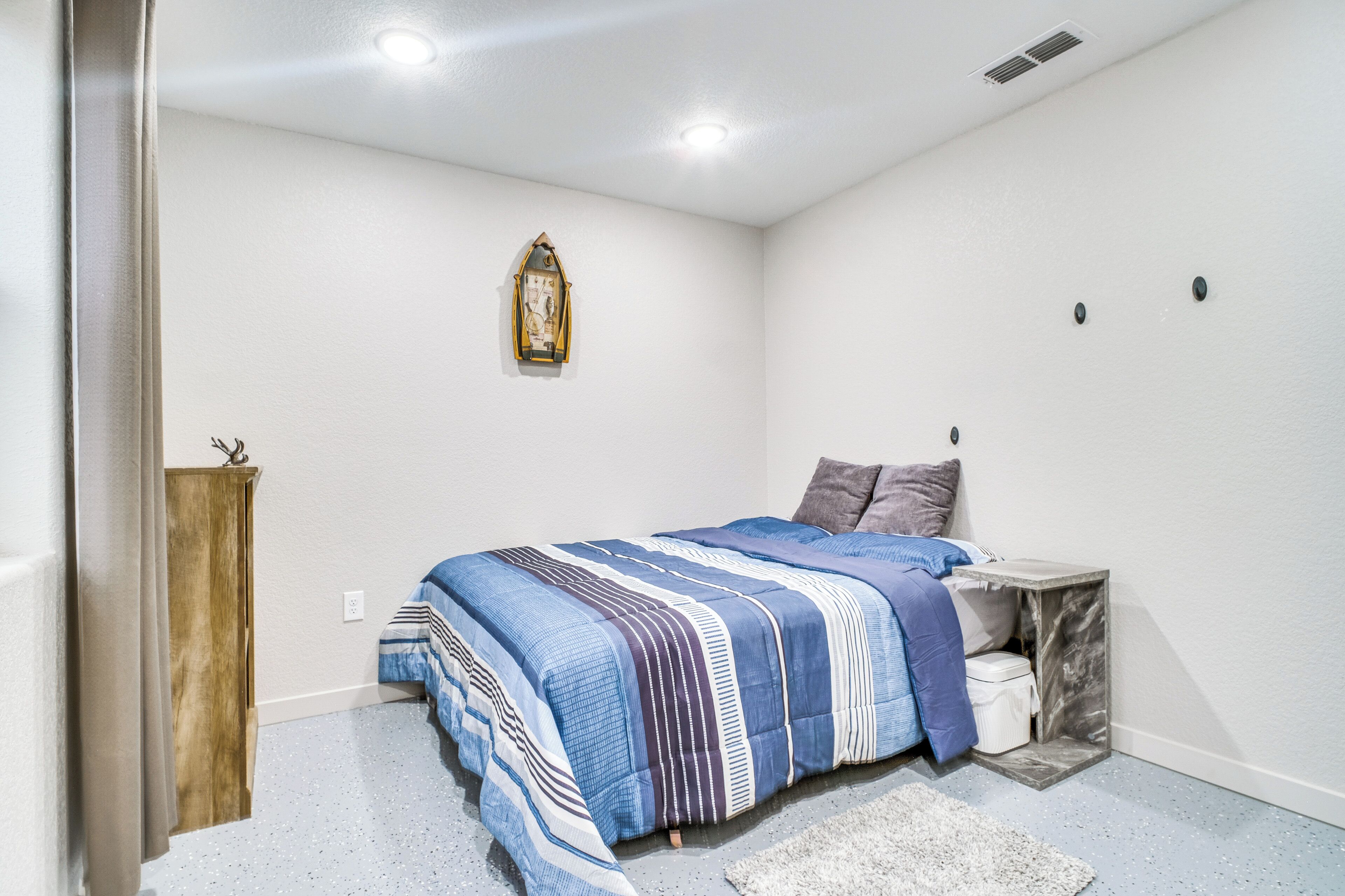 Een slaapkamer met een bed, nachtkastje, houten kast, wandklok en wit plafond.
