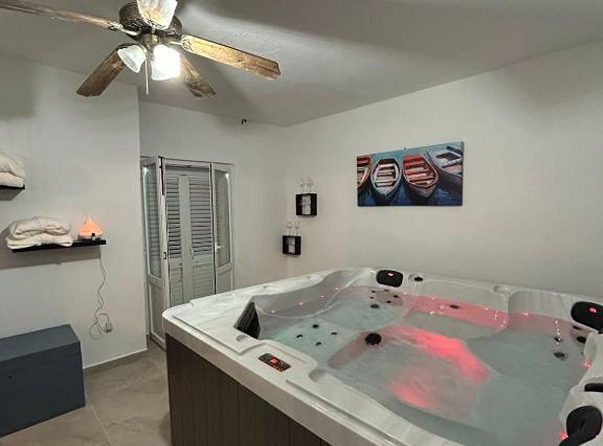 Quarto de spa com hidromassagem, ventoinha no teto, obras de arte e porta-toalhas.