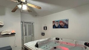 A spa room with a hot tub, ceiling fan, artwork, and a towel rack. - Lanterna Apartment With Hot-tub (Orebic)