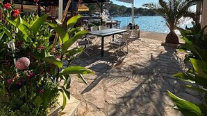 An outdoor patio with stone flooring, a table, chairs, and potted plants. - Lanterna Apartment With Hot-tub (Orebic)