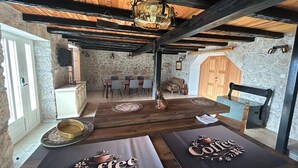 A rustic dining area with a stone wall, wooden ceiling beams, and a chandelier. - Lanterna Apartment With Hot-tub (Orebic)