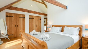 Ein Schlafzimmer mit einem hölzernen Bett, einem Schrank aus Holz, einem Spiegel und einem Nachttisch mit Lampe.