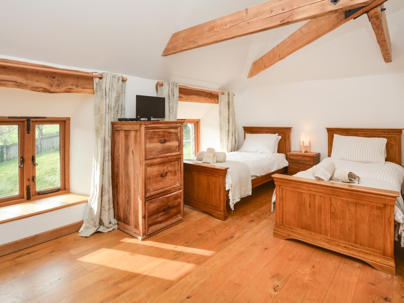 A bedroom with a wooden bed, a nightstand, a dresser, and a TV.