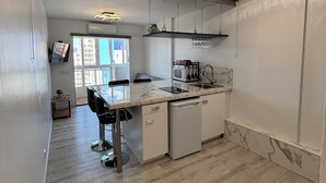 Une cuisine compacte comprenant un coin repas, un four à micro-ondes encastré, un évier et un lave-vaisselle.