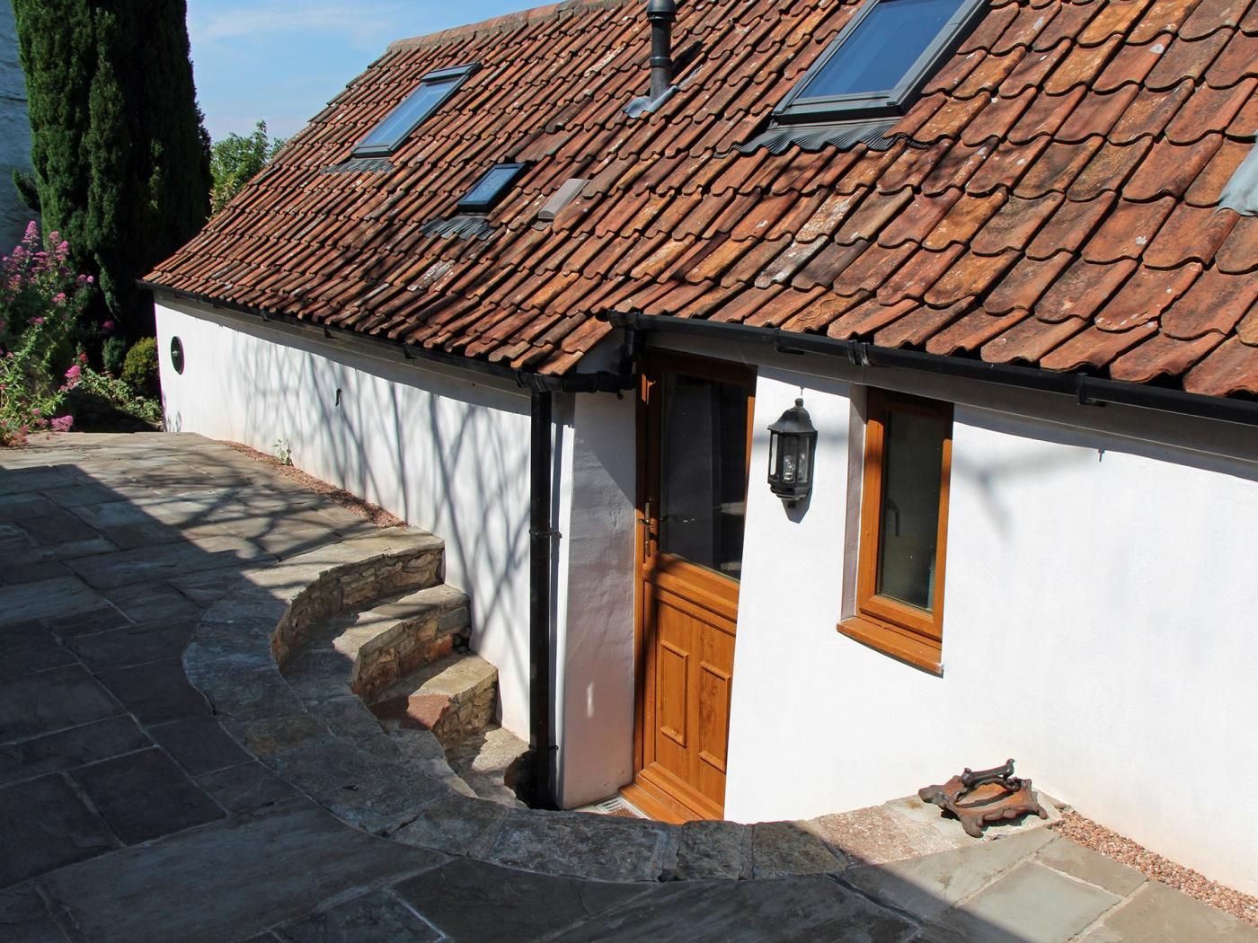 A house with a tiled roof, a wooden door, and a stone staircase leading to the entrance.