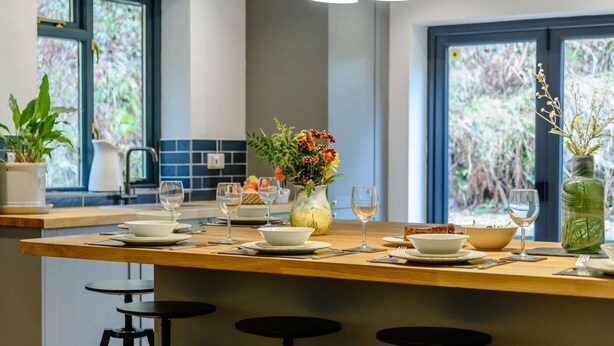 Una cocina moderna con una isla central, iluminación colgante y ventanas amplias.