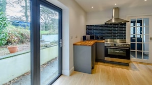 Una cocina moderna con un amplio ventanal corredera, una estufa de acero inoxidable y un salpicadero de azulejos azules.