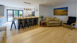 Una cocina moderna con barra, sofá y una silla en una sala de estar con un cuadro grande en la pared.
