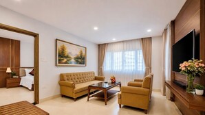 Uma sala de estar moderna com sofá, poltrona, mesa de centro, televisão e um quadro na parede.