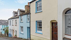 Eine Reihle traditioneller Häuser mit ausgeprägten Baustilen, darunter ein markanter Schornstein und verschiedene Fenstergestaltungen.