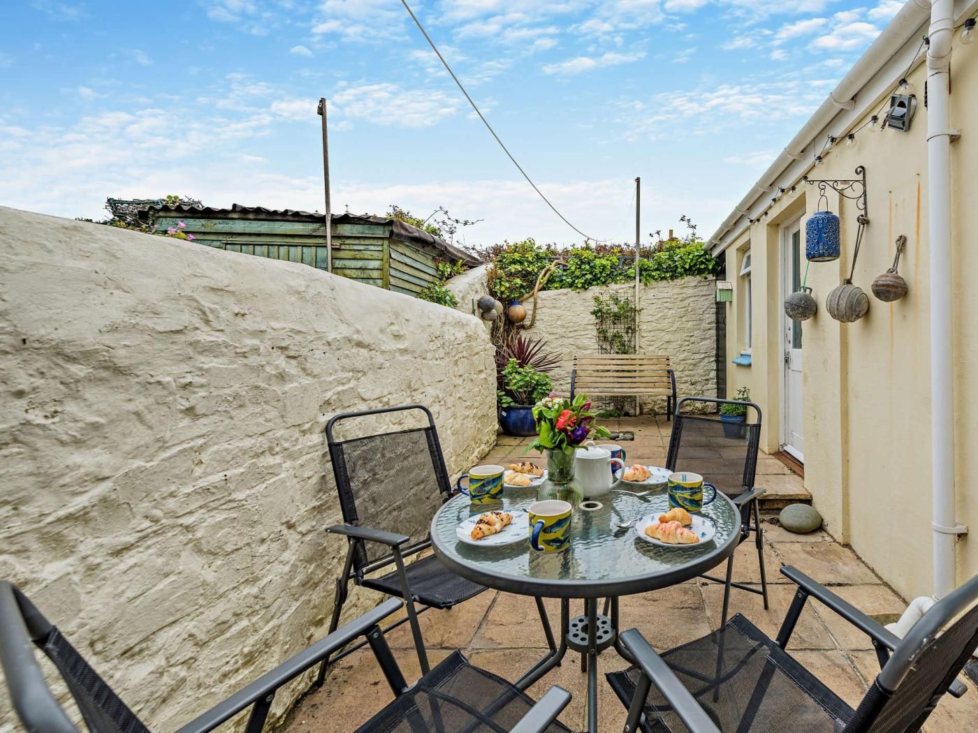 A patio with a round table set for dining, surrounded by chairs.
