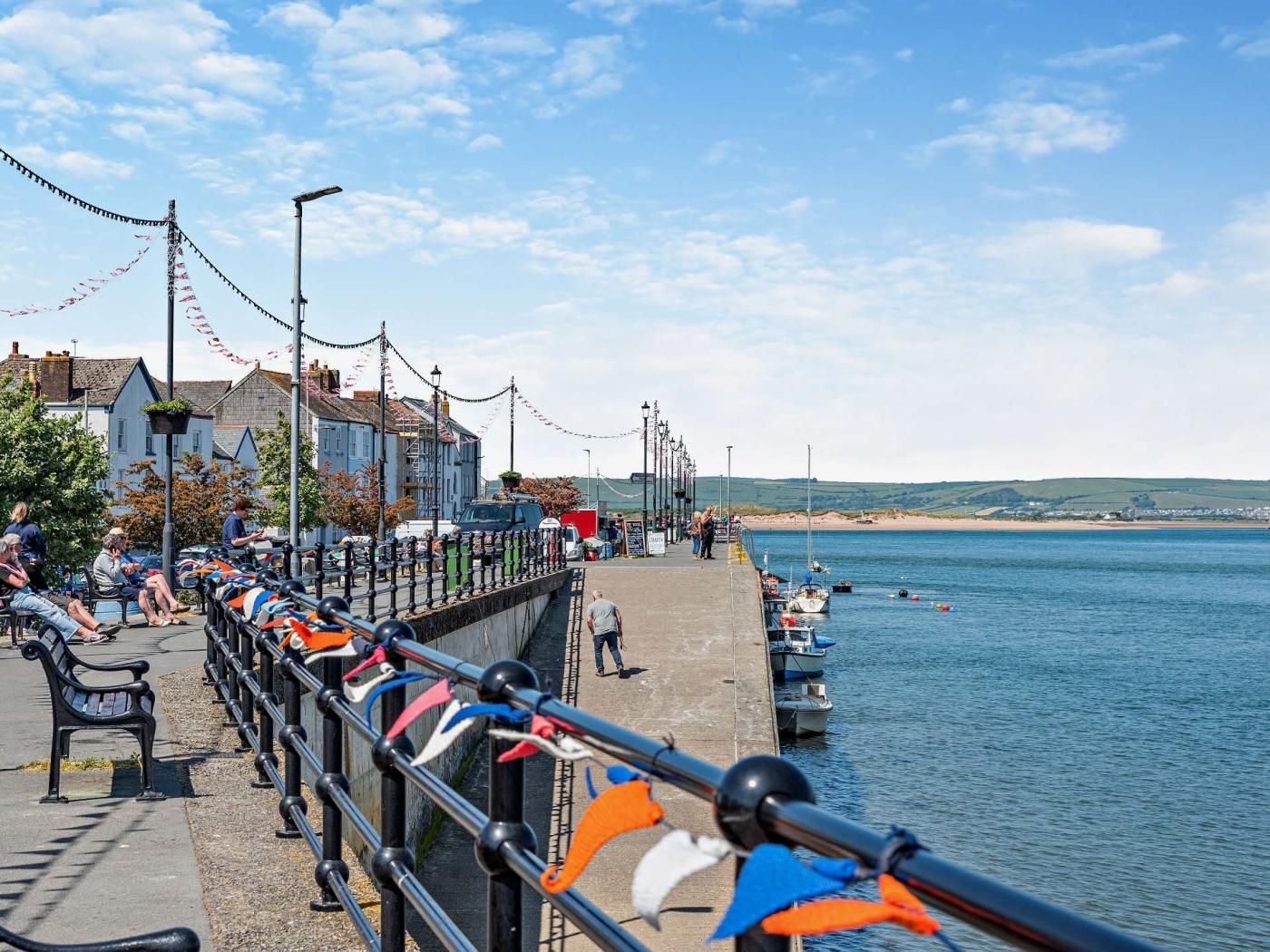 Une promenade en bord de mer, agrémentée d’une balustrade, de bancs et offrant une vue sur la mer.
