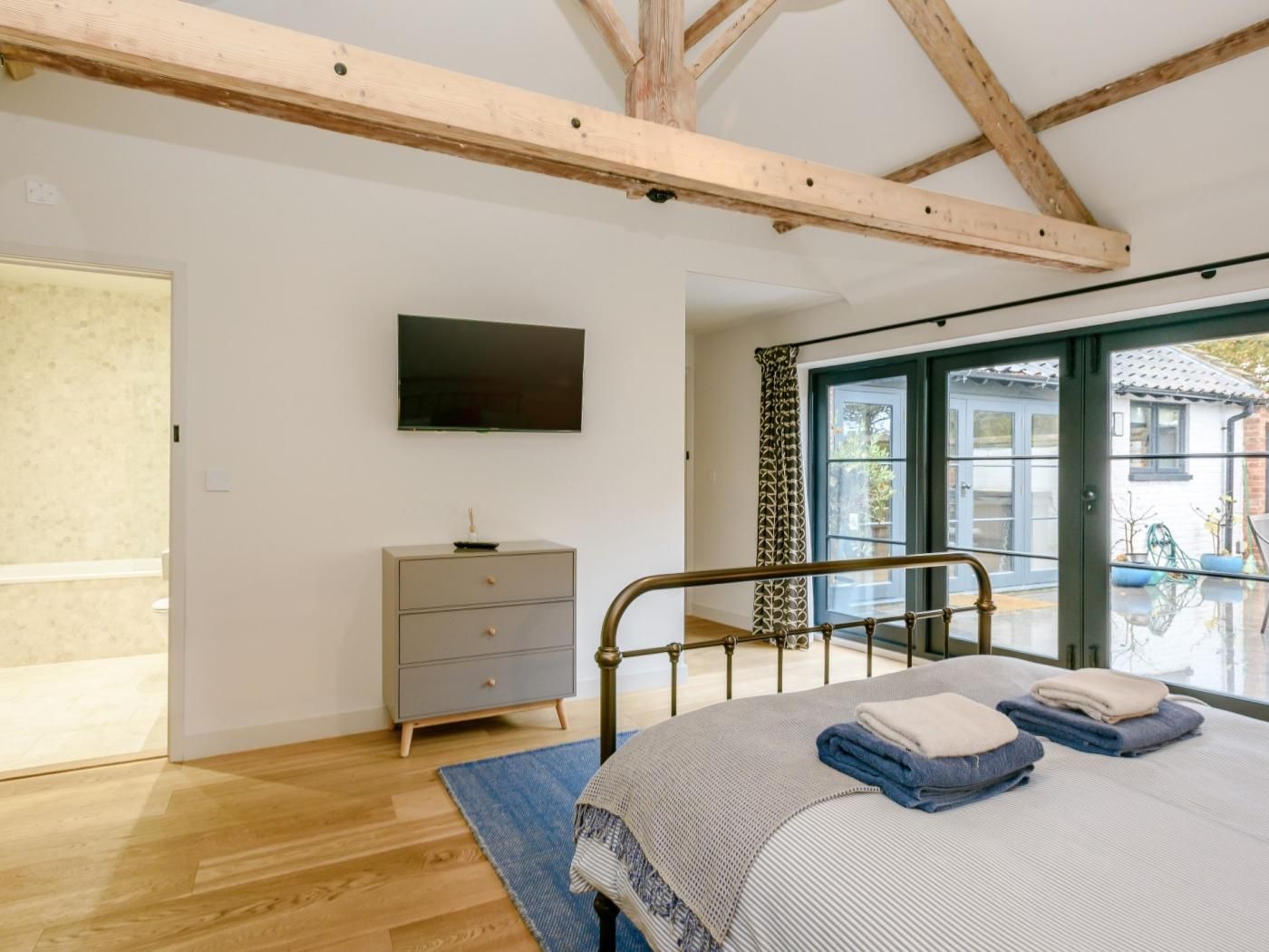 Une chambre à coucher comprenant un lit, une commode, un téléviseur et une porte-fenêtre coulissante donnant sur un espace extérieur.