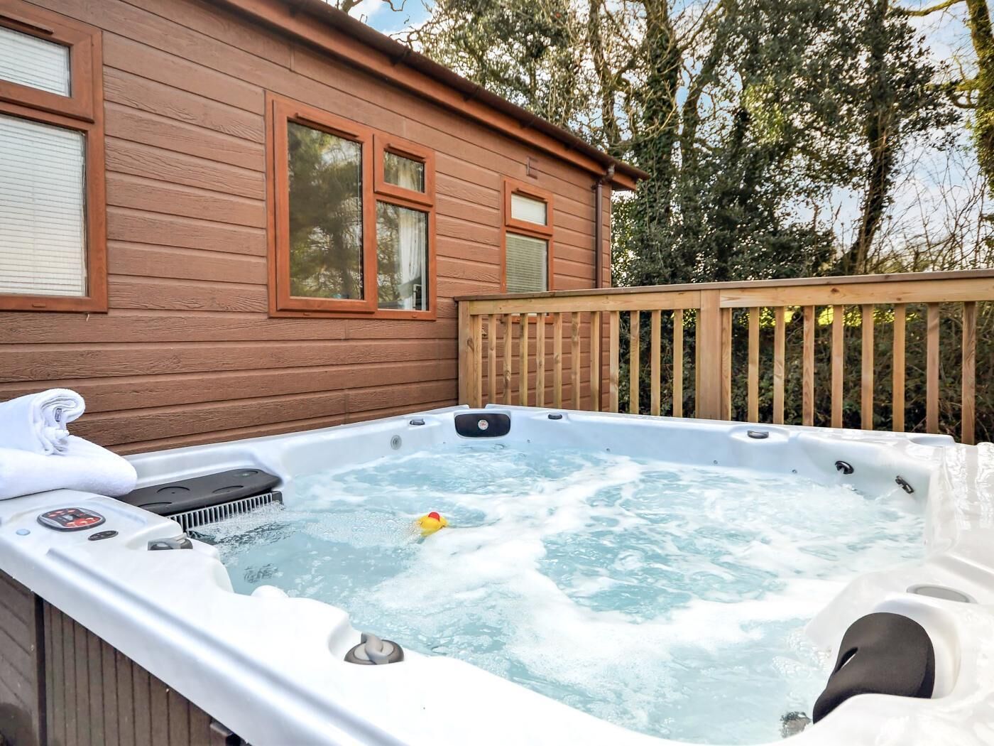 A hot tub with a wooden deck and a house in the background.
