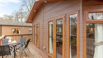 Une cabane en bois avec une terrasse, une table à manger avec des chaises et une grande porte-fenêtre coulissante.