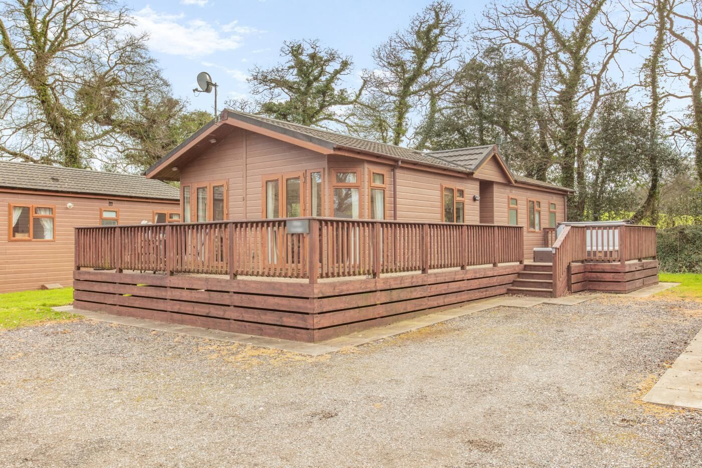 Une cabane en bois avec une terrasse, une antenne parabolique et un petit espace extérieur.