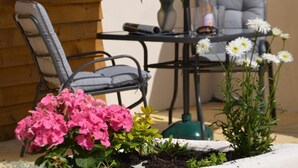 Eine Terrasse mit Tisch, Stühlen, einem Blumentopf und Blumen.