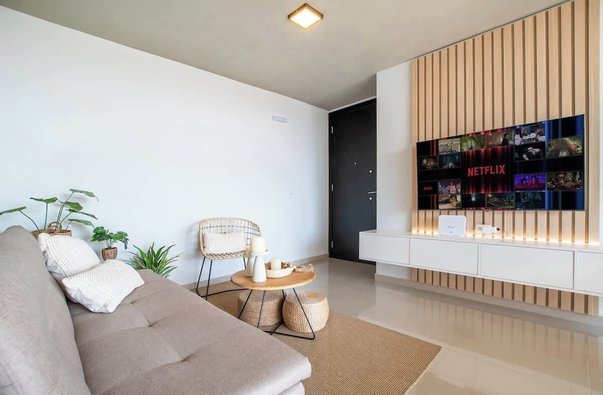 A modern living room with a sofa, a round coffee table, and a wall-mounted TV displaying Netflix content.