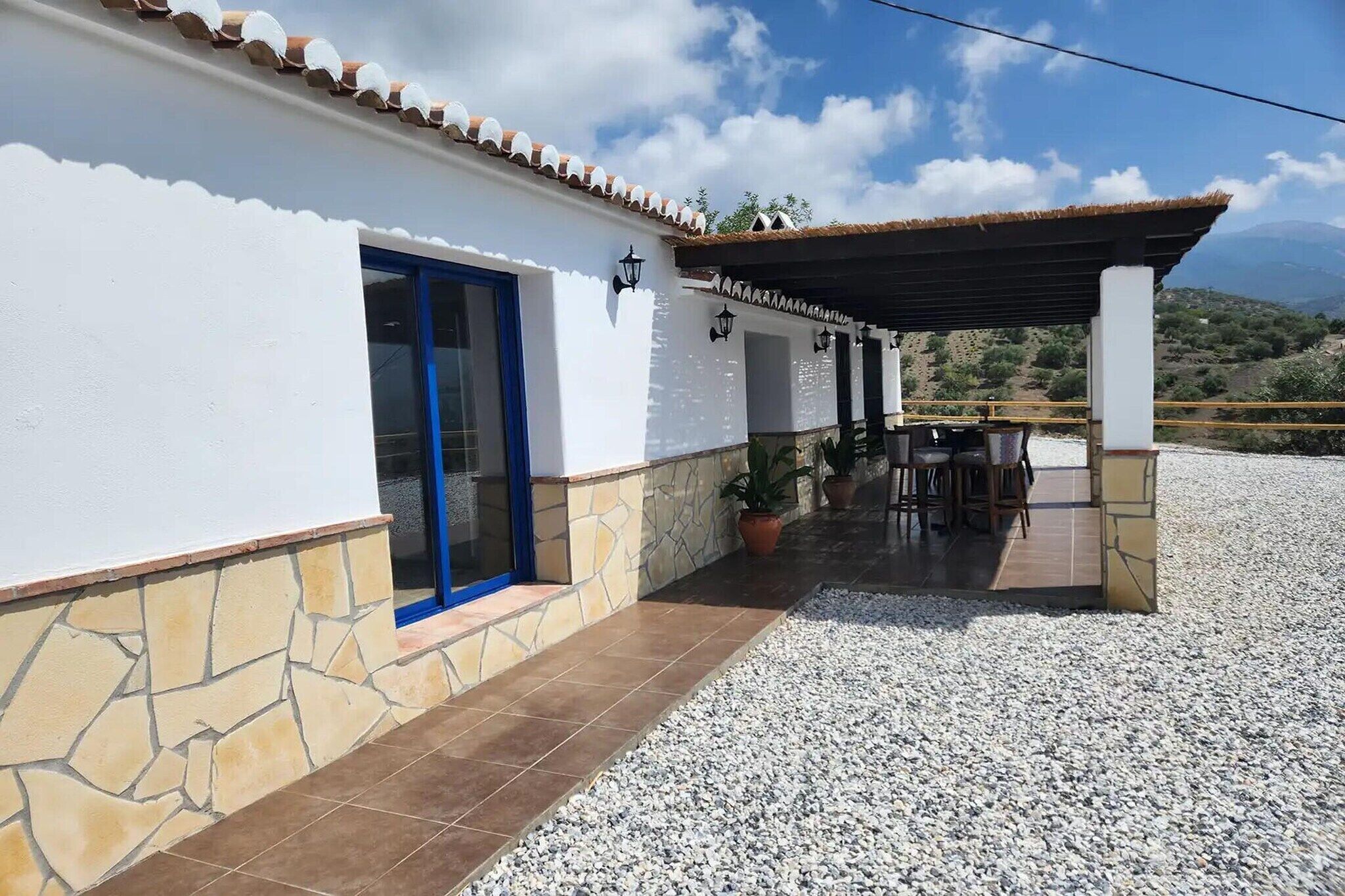 A building with a white exterior, a blue door, and a covered patio area with a table and chairs.