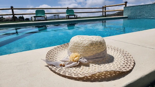 Uma área à beira da piscina com um chapéu de palha e um laço decorativo.