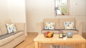 A living room with a sofa, a coffee table with fruit, a lamp, and a window with blinds. - 1 Bed in Kelso (oc-52538) (Morebattle)